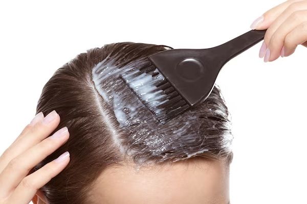 Coloration des cheveux avec une brosse sur un mur blanc