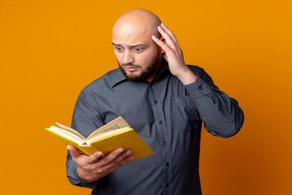 Homme regardant un livre avec surprise