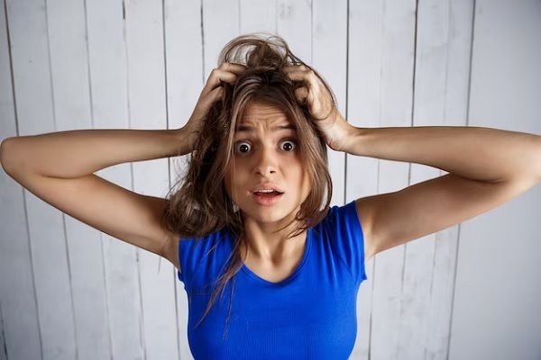Femme se tenant les cheveux dans les mains sur un mur en bois blanc. Cheveux à faible volume