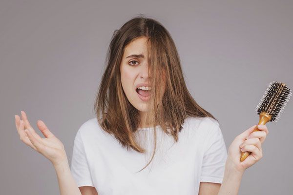 Femme aux cheveux en désordre, une brosse à la main. , Chute de cheveux