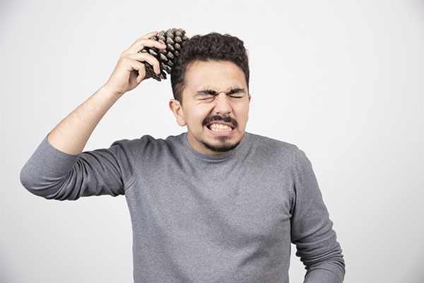 Un jeune homme pose une pomme de pin au-dessus de sa tête. le Minoxidil 5