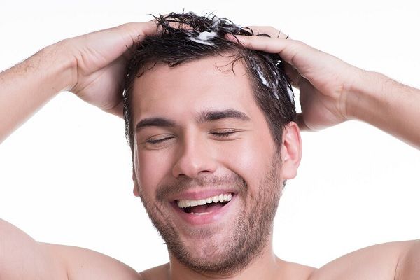 Jeune homme souriant heureux, se lavant les cheveux avec les yeux fermés. shampooing ketoconazole