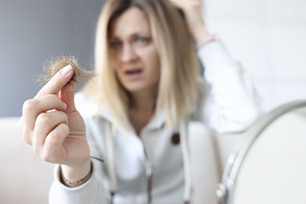 Une femme frustrée tient un chignon de cheveux dans sa main.