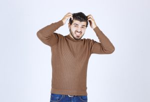 Photo d'un jeune mannequin séduisant, debout, regardant l'appareil photo sur un mur blanc. Photo de haute qualité