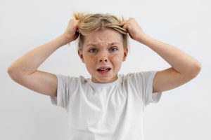Garçon de face se tenant les cheveux