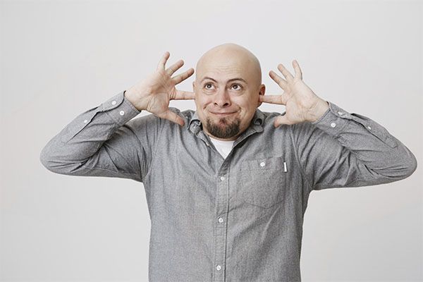Un chauve énervé se ferme les oreilles à cause d'un bruit trop fort. santé mentale impact cheveux
