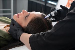 Jeune femme ayant un problème de cheveux recevant une injection dans la peau de la tête dans une clinique de mésothérapie