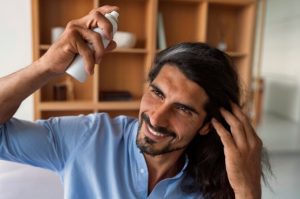 Plan moyen d'un homme utilisant un shampoing sec à la maison