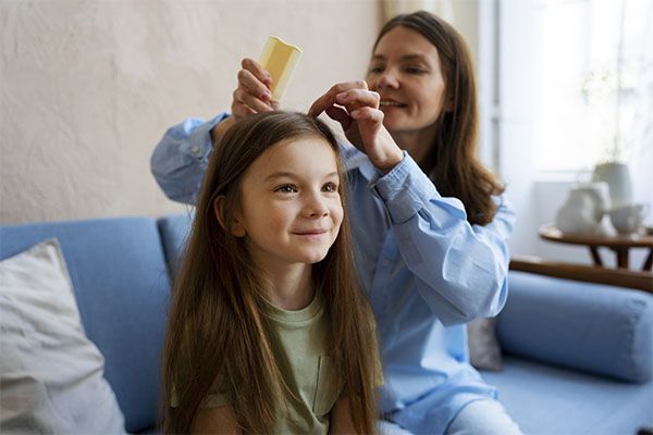 Une femme âgée utilise un peigne jaune pour brosser le cuir chevelu d'une jolie fille.