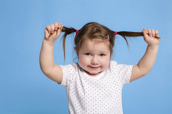 Belle fille en chemise noire à pois et se tenant les cheveux dans les mains. l'alopécie infantile