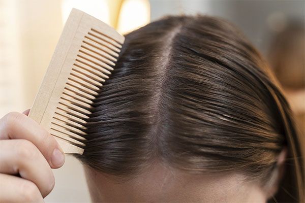Femme brune se coiffant avec un peigne beige. Ronquina