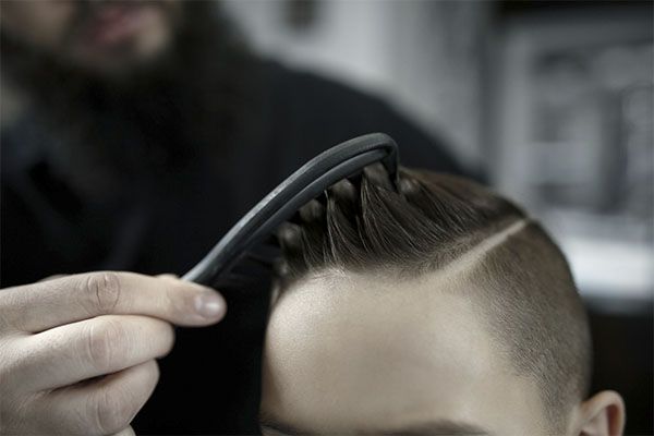 Un coiffeur coiffe un homme aux cheveux crépus