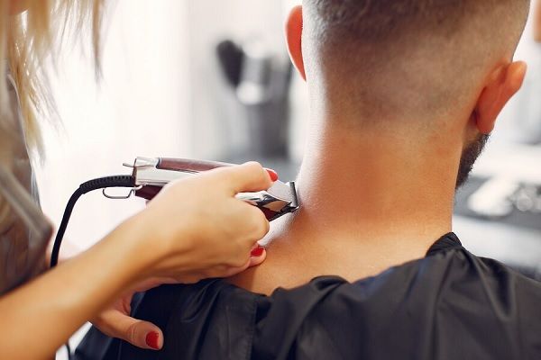 Femme rasant les cheveux d'un homme dans un salon de coiffure. Coupes de cheveux pour les hommes aux cheveux dégarnis
