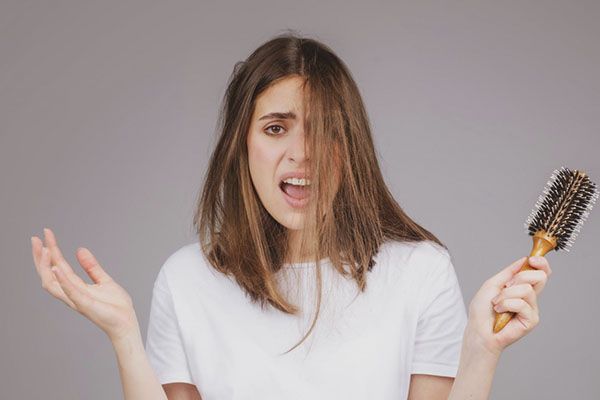 femme en chemise blanche, l'air inquiet, un pinceau à la main.