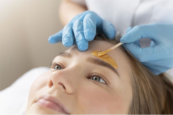 Médecin spécialiste pratiquant une intervention esthétique sur une belle femme aux yeux clairs.