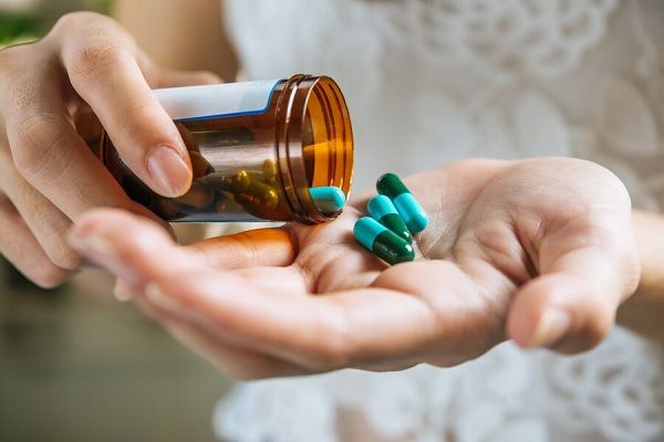 La main d'une femme verse des pilules médicinales hors de la bouteille 