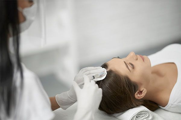 Femme dans une clinique se faisant examiner le cuir chevelu par un médecin spécialiste des greffes de cheveux.