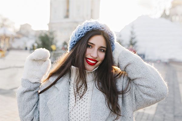 Femme heureuse aux lèvres rouges portant des manteaux de froid posant pour une photo. 