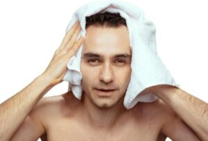 Portrait d'un homme avec une serviette de bain blanche après la douche, isolé sur fond blanc, en studio.