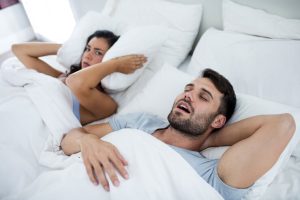 Femme agacée par un homme qui ronfle dans son lit dans une chambre à coucher