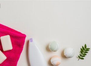 Savon ; bombe de bath ; crème hydratante et serviette rose avec feuilles sur fond blanc