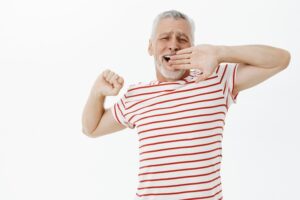 Une personne âgée bâille et s'étire après une bonne sieste.