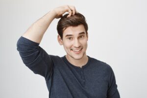 Un garçon désemparé surpris en train de sourire et de se gratter la tête