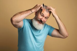 Plan moyen, homme se coiffant, chute cheveux racines blanches
