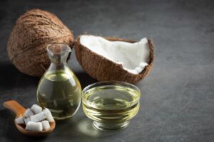 Pichet d'huile de coco avec noix de coco sur fond sombre