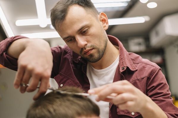 Coiffeur effectuant une coupe de cheveux à un client