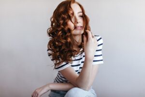 Adorable femme pensive en t-shirt rayé regardant au loin. Photo d'intérieur d'une femme glamour en pain d'épices.