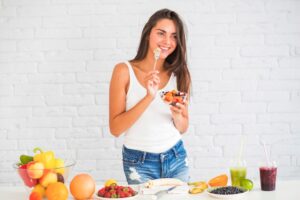 Jeune femme souriante mangeant une salade de fruits saine 
