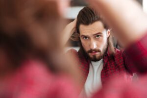 Homme en chemise à carreaux debout et se regardant dans un miroir