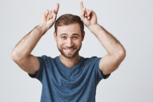 Homme heureux et beau faisant des cornes de diable sur le dessus de la tête