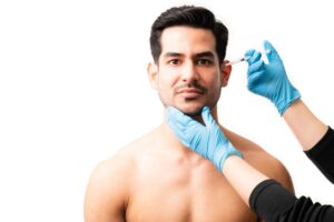 Gros plan des mains du médecin injectant du botox dans la peau du modèle masculin sur fond blanc.