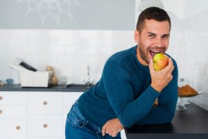 Homme souriant mangeant une pomme à la maison