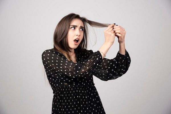 Une belle jeune femme tenant ses cheveux sains et brillants. Quelle est l’ampleur normale de la perte de cheveux chez les femmes 