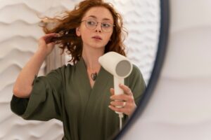 Femme utilisant un sèche-cheveux pendant son rituel de beauté. Mythes sur les cheveux