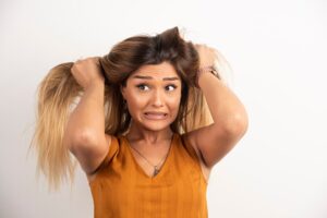 Jeune femme se touchant les cheveux et posant sur fond blanc.