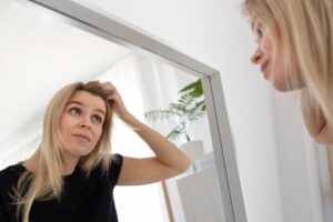 Femme avec pellicules se regardant dans un miroir.