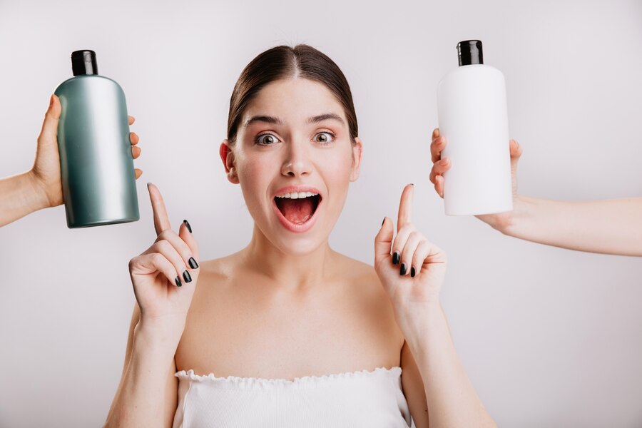 Portrait en gros plan d'une jeune fille joyeuse posant sans maquillage sur un mur blanc. Une femme choisit le meilleur shampoing à utiliser. meilleurs shampoings pour cheveux gras
