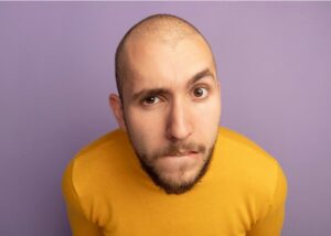 Jeune garçon au regard suspicieux regardant droit devant lui isolé en violet.